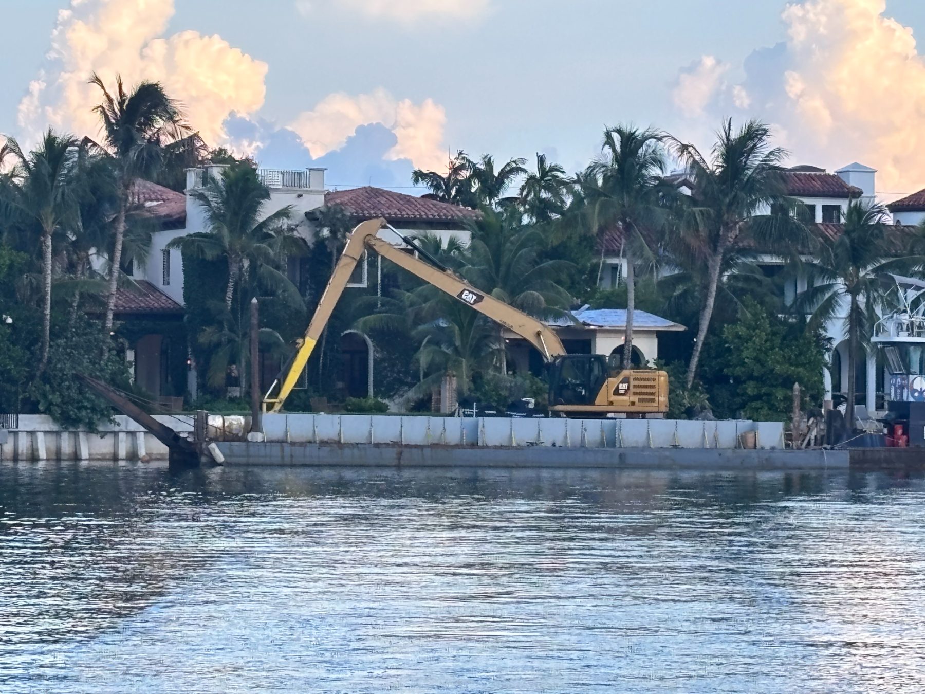 Long-reach excavator dredging alongside a Miami Beach seawall